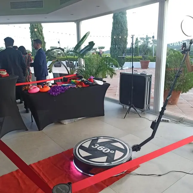 Plataforma 360 giratoria montada sobre alfombra roja en una boda, con mesa de atrezo y flycase de transporte